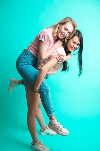 Дві грайливі міжрасові дівчата свинарство і розваги в студії — стокове фото
