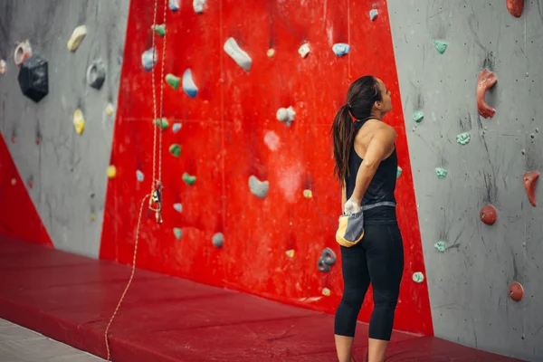 Женщина смотрит на стену для скалолазания в спортзале — стоковое фото