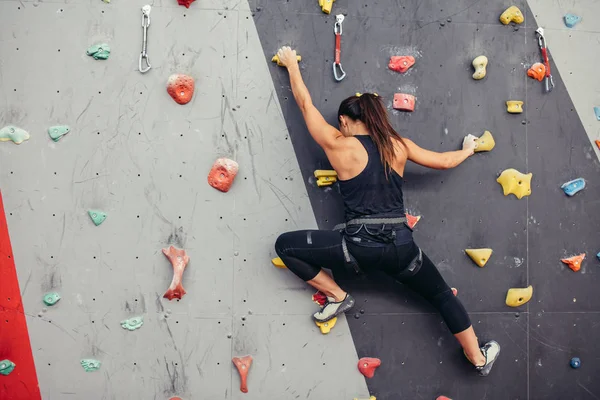 Jeune grimpeuse grimpant sur un rocher pratique au centre d'escalade, bloc — Photo