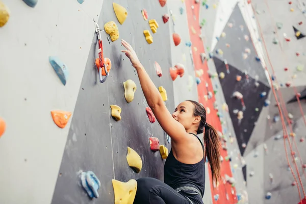 Αθλητική νεαρή γυναίκα εκπαίδευση σε ένα πολύχρωμο γυμναστήριο αναρρίχησης. — Φωτογραφία Αρχείου