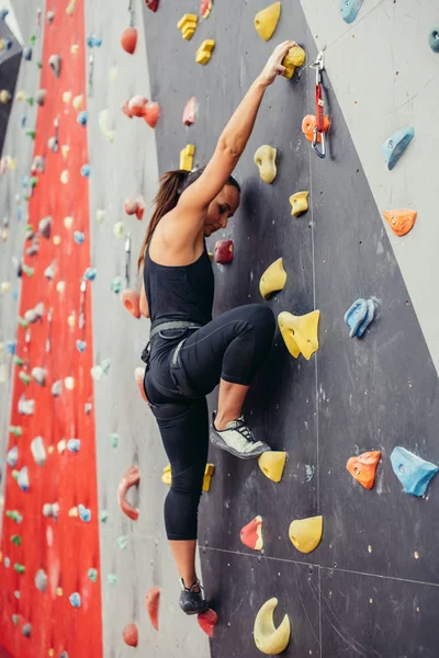 Спортивна молода жінка тренується в барвистому скелелазіння спортзалі . — стокове фото
