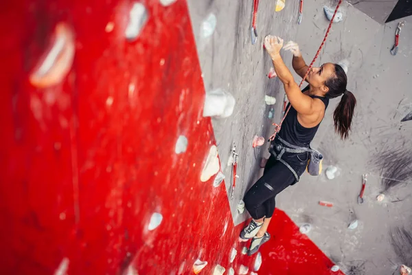 Mujer joven haciendo bouldering profesional en gimnasio de escalada en interiores — Foto de Stock