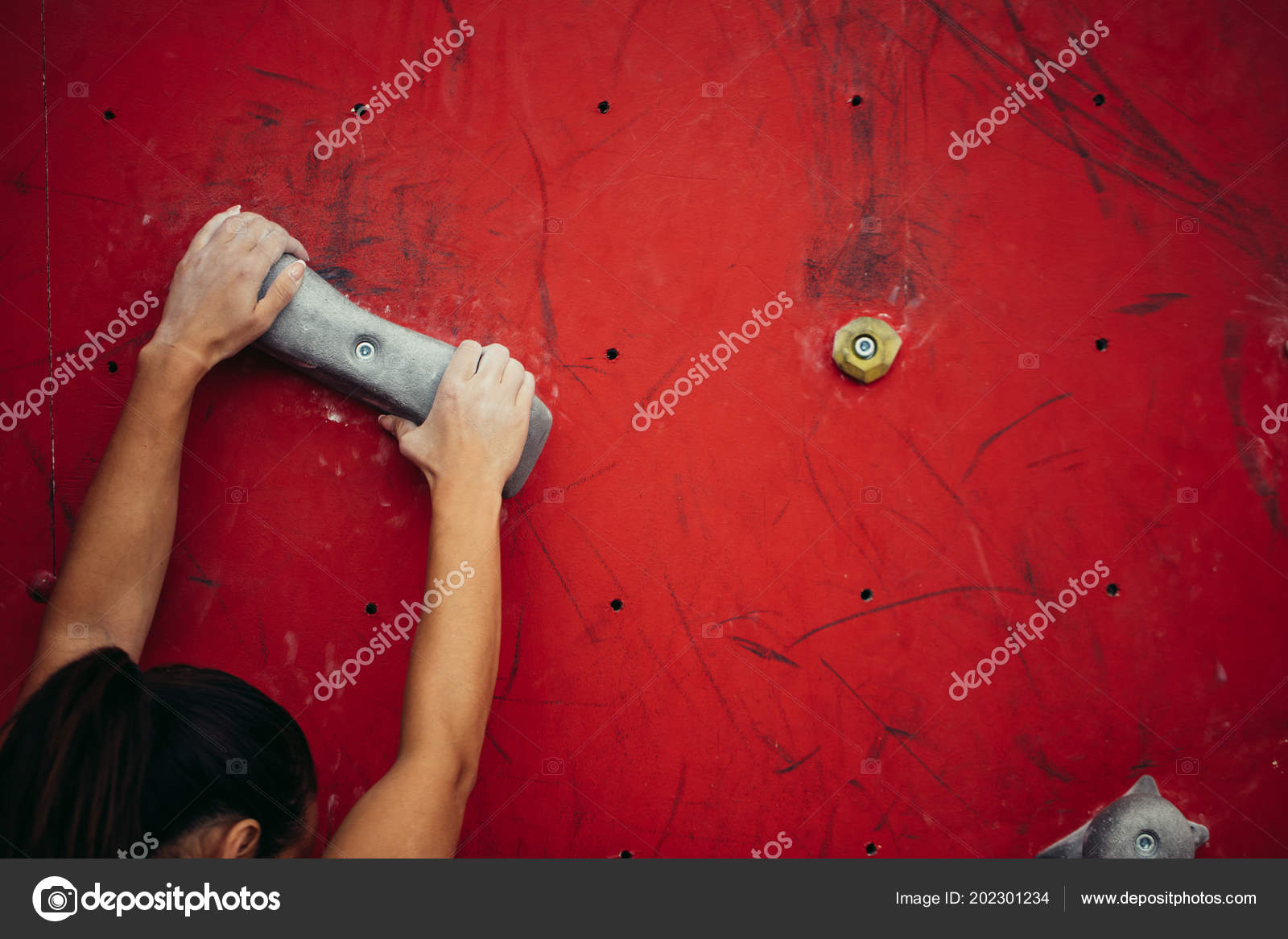 Female climber hands holding artificial boulder in climbing gym