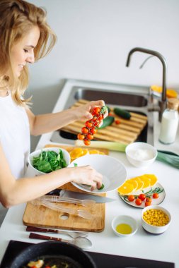 Kadın taze sebzelerden sağlıklı salata yapıyor.