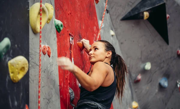 Güzel, genç ve güçlü bir kadın kırmızı duvar üst manzarasına tırmanıyor..