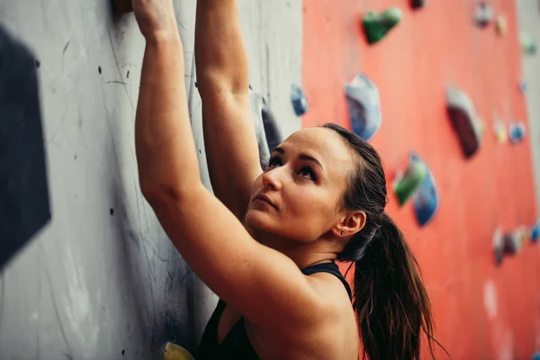 Piękna młoda silna kobieta wspinaczka na czerwonej sztucznej ścianie widok z góry. — Zdjęcie stockowe