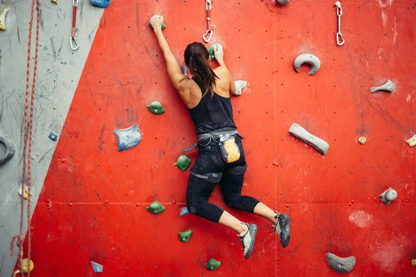 Hermosa joven mujer dando un gran paso por una pared artificial — Foto de Stock