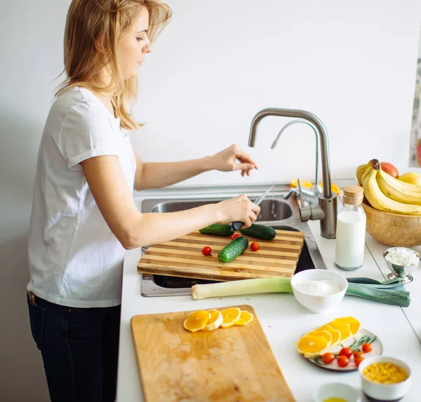 Jeune femme nettoie la vaisselle dans la cuisine — Photo