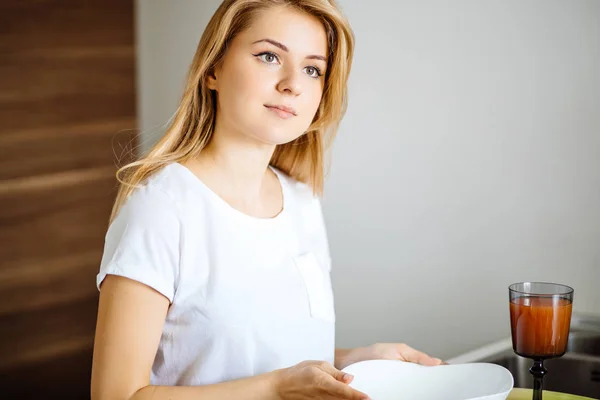 Atractiva mujer rubia posando en la mesa en su cocina — Foto de Stock