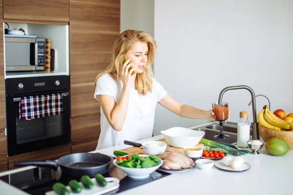 Frau macht gesunde Mahlzeit und liest Nachricht am Telefon in der heimischen Küche. — Stockfoto