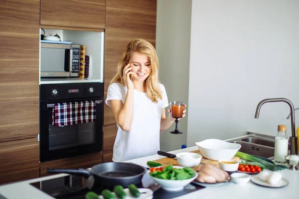 Mujer haciendo comida saludable y leyendo el mensaje en el teléfono en la cocina doméstica. — Foto de Stock