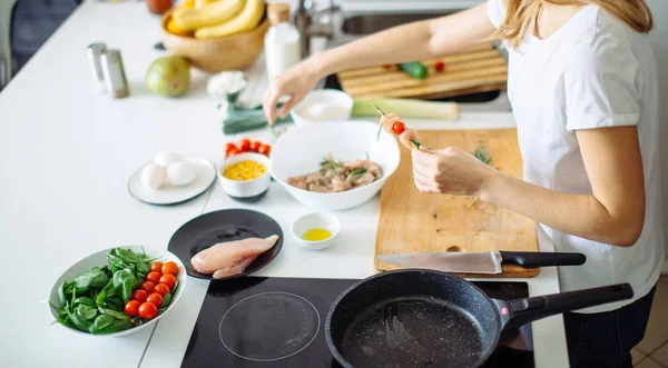 Mujer haciendo kebabs de carne y verdura en la tabla de cortar en la cocina — Foto de Stock