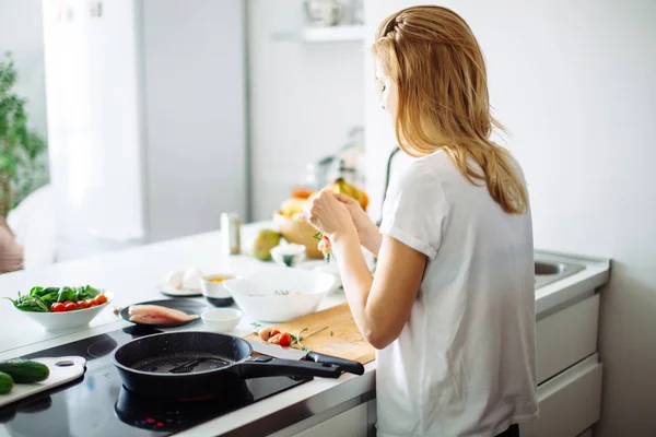 Junge Hausfrau kocht in der Küche Mahlzeit für Hausfrauen. Rückansicht — Stockfoto