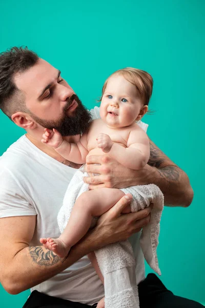 Oynak babası onun gülümseyen bebek çocuk boynuna mavi arka plan üzerinde taşıyor. — Stok fotoğraf