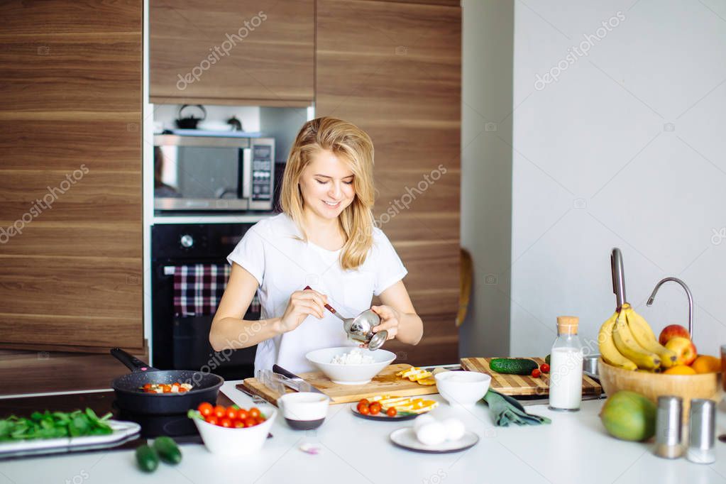 Woman mixing delicious superfood salad ingredients with wooden spoons in kitchen