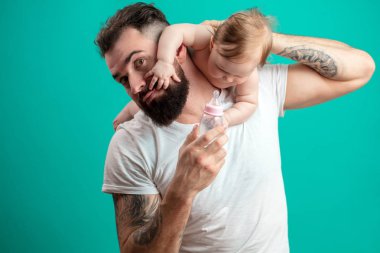 Oynak babası onun gülümseyen bebek çocuk boynuna mavi arka plan üzerinde taşıyor.