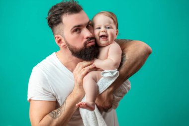 Oynak babası onun gülümseyen bebek çocuk boynuna mavi arka plan üzerinde taşıyor.