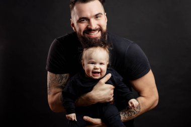 Siyah arka plan üzerine bebek ile genç atletik baba