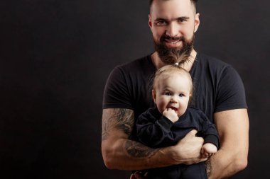 Siyah arka plan üzerine bebek ile genç atletik baba