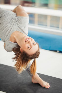 Yoga yapan kadın, fitness merkezinde üçgen pozu veren.