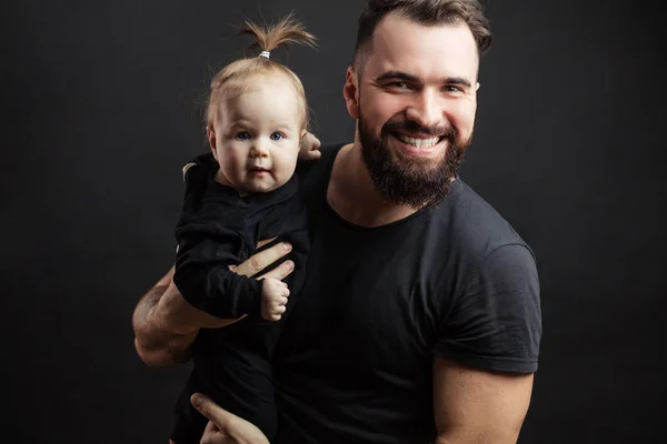 Jovem pai atlético com bebê adorável no fundo preto — Fotografia de Stock