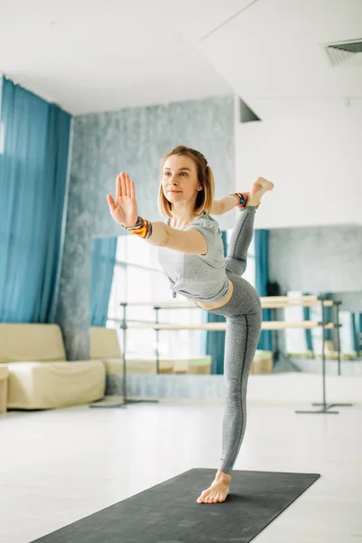 Joven mujer en forma haciendo una pose de yoga de pie con una pierna levantada. — Foto de Stock