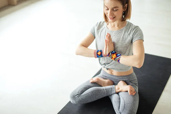 Deportiva mujer sentada con piernas cruzadas en pose de loto en habitación luminosa — Foto de Stock