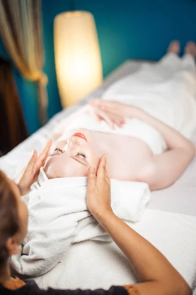 Jovem mulher bonita desfrutando de procedimento de massagem facial — Fotografia de Stock