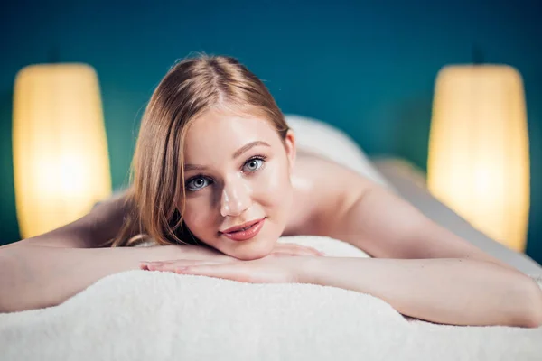 Young, beautiful woman in spa salon lying on massage table waiting for massage.