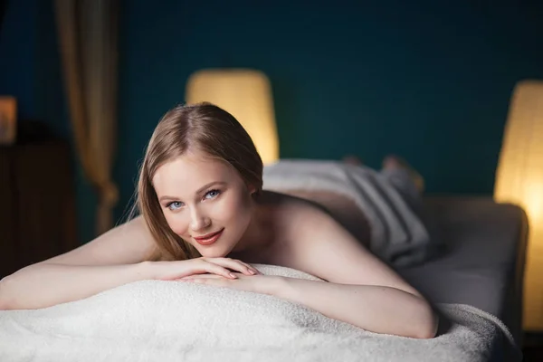 Mladá, krásná žena v lázeňském salonu ležící na kočáře a čekající na masáž. — Stock fotografie
