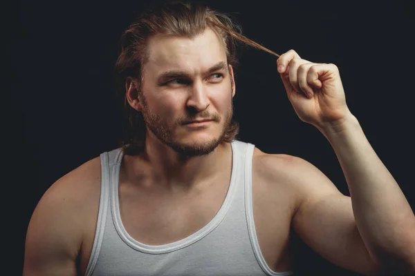 El joven está tirando de su pelo rubio en el estudio. retrato de primer plano —  Fotos de Stock