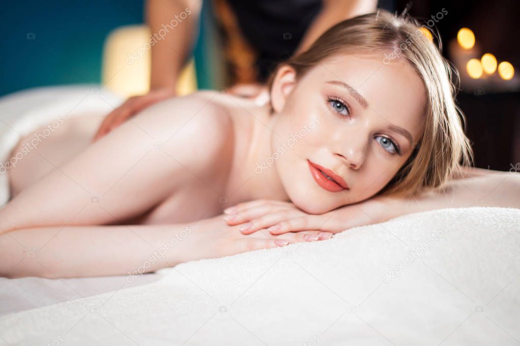 Beautiful, young and healthy woman is having hot stone massage. Spa Treatment