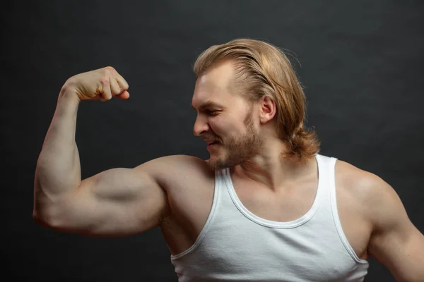 Allegro maschio sportivo guardando il suo braccio muscolare — Foto Stock
