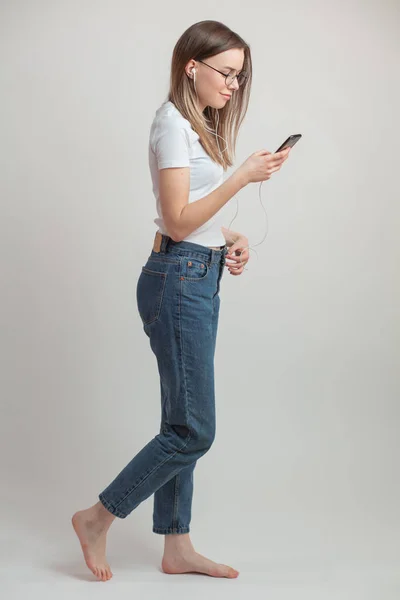Full length side view portrait of young woman walking and listening to the music — Stock Photo, Image