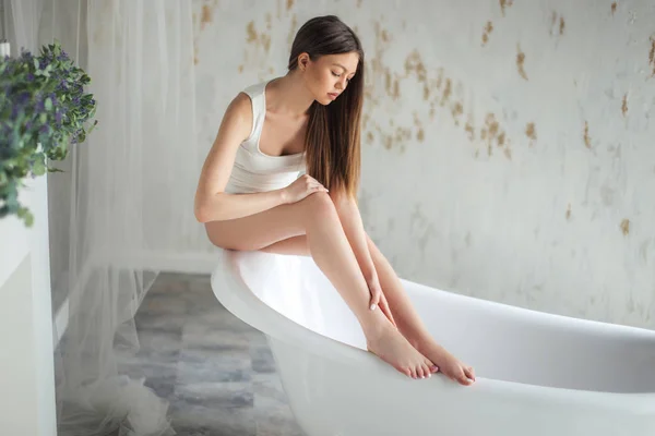 Cerrar retrato chica atractiva mirando sus piernas después de poner crema — Foto de Stock