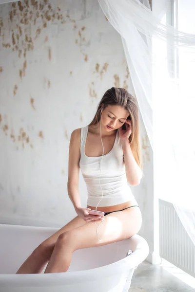 Pleasantgirl listening to the music while washing her legs in the tub — Stock Photo, Image