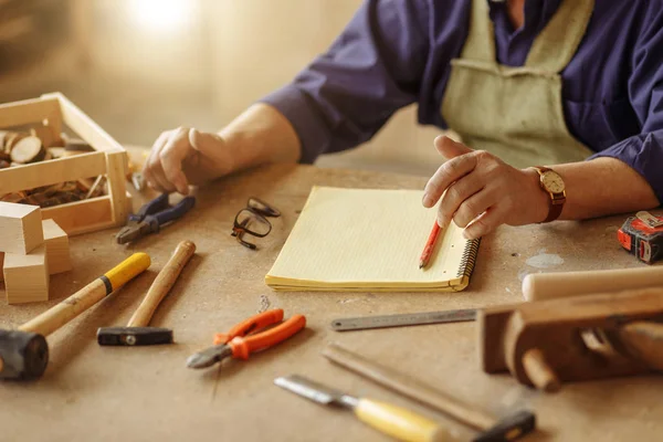 El yapımı çalışmaları için çeşitli enstrümanlar ile tahta masada oturan usta