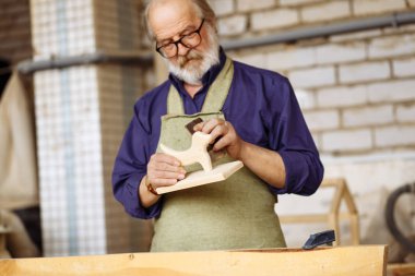 kıdemli vatandaş ahşap oyuncak zımpara ile daha yumuşak yapıyor