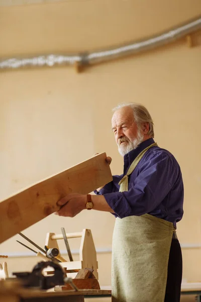 Grijs hoofd oud mannetje werkt met natuurlijke hout — Stockfoto