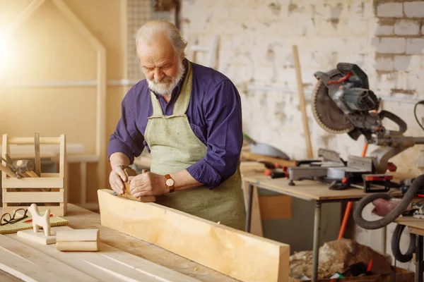 Senior-Schreiner glättet die Kante von Holzplanken — Stockfoto