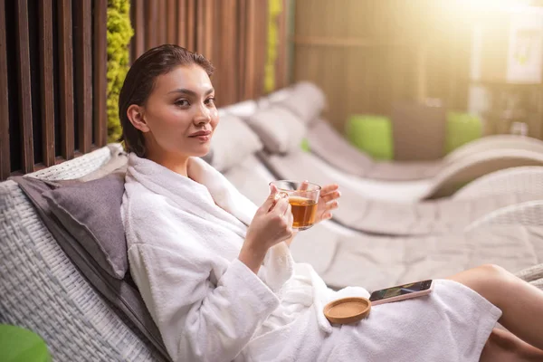 Молода жінка сидить у вітальні після прийняття ванни з чашкою трав'яного чаю — стокове фото