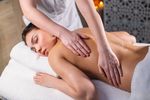 Ung vacker kvinna med slutna ögon tar emot massage för hela kroppen — Stockfoto