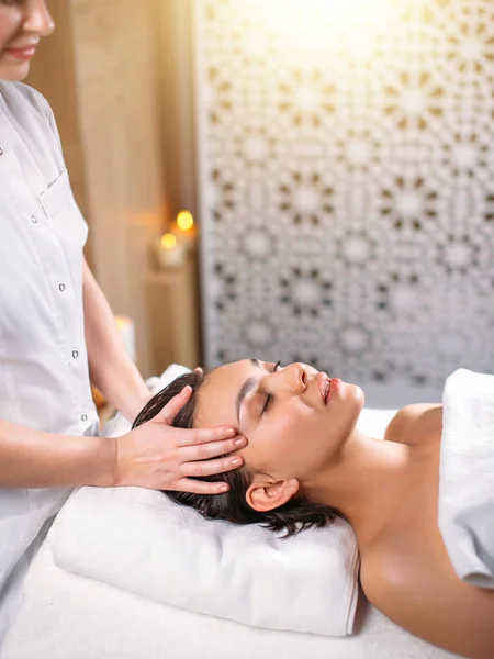 Chica guapa con los ojos cerrados recibiendo masaje en la cabeza en el salón de spa — Foto de Stock