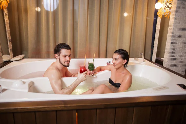 Gyönyörű pár pihentető és inni koktélt magát a pezsgőfürdőben, a szálloda — Stock Fotó