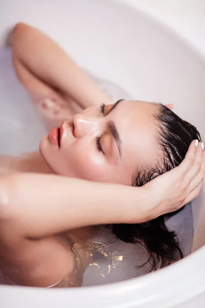 Мокрая красивая девушка трогает свои волосы в ванне — стоковое фото