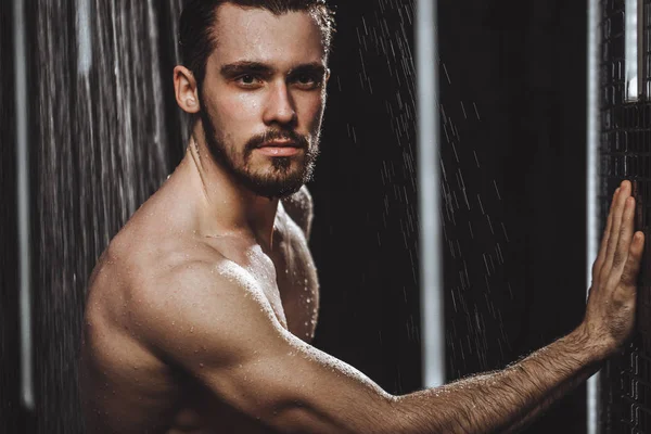 Bearded black-haired man looking at the camera while taking a shower — Stock Photo, Image