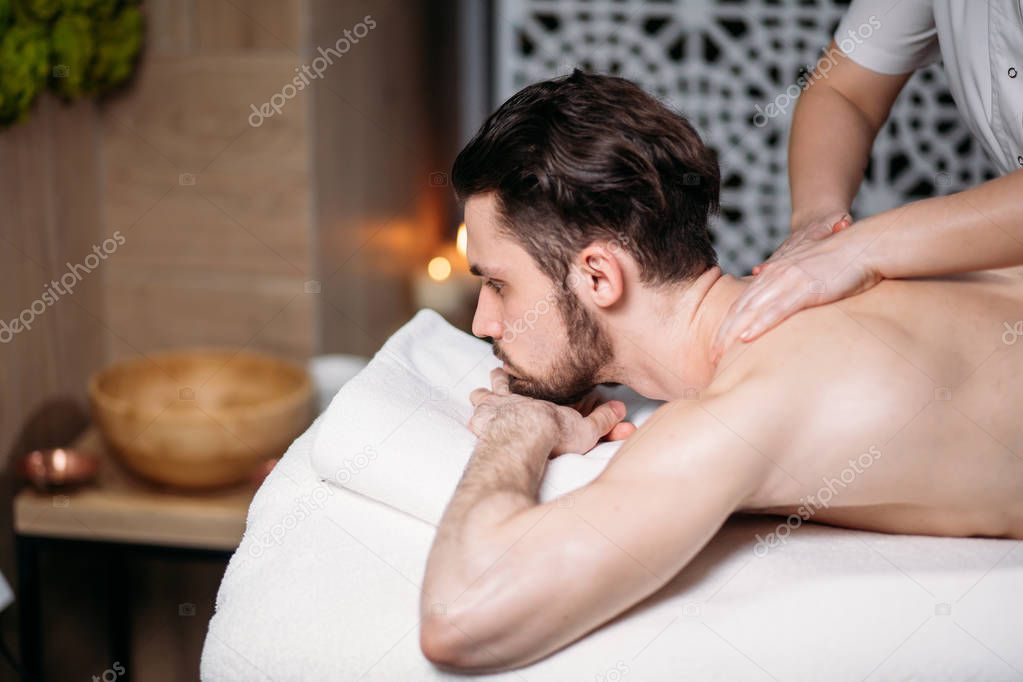 sportsman is receiving back massage in spa room
