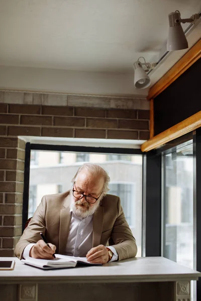 Foto ravvicinata di un uomo anziano che scrive nel suo diario personale nella sala studio — Foto Stock