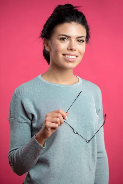 Cheerful beautiful model holding glasses and looking at the camera — Stock Photo, Image