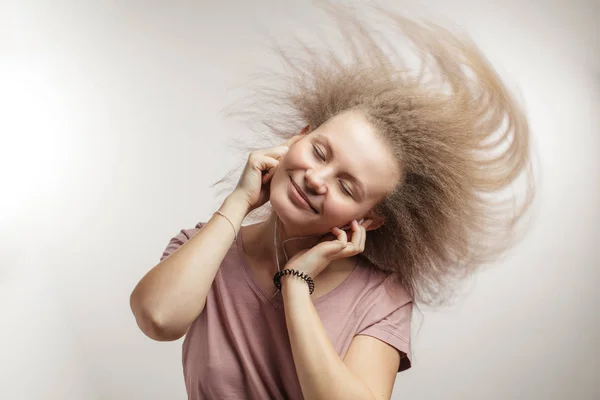 Летающие волосы. молодая очаровательная женщина с пушистыми волосами в наушниках — стоковое фото